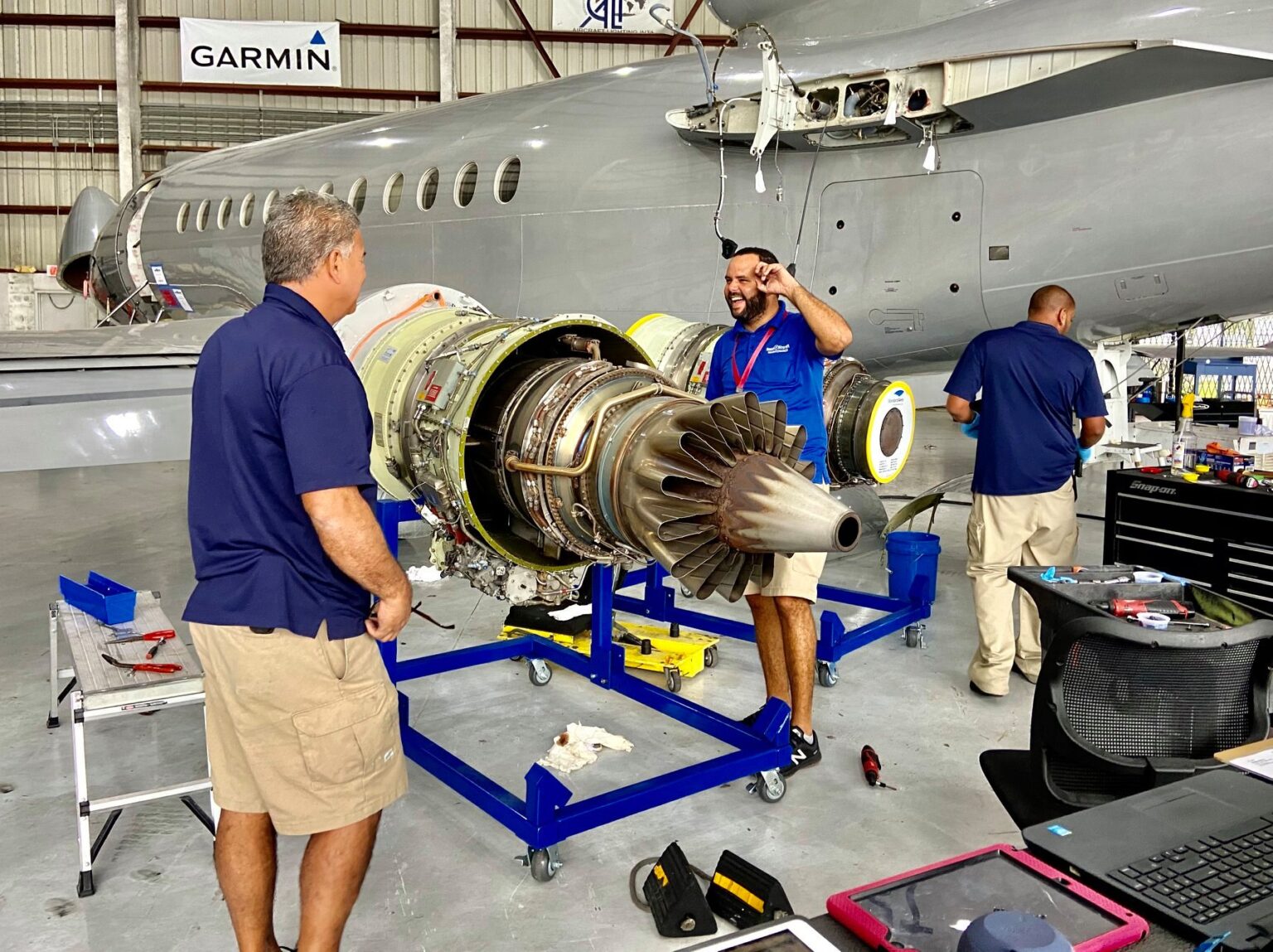 Three BAM Aircraft mechanics next to a dismantled jet engine.